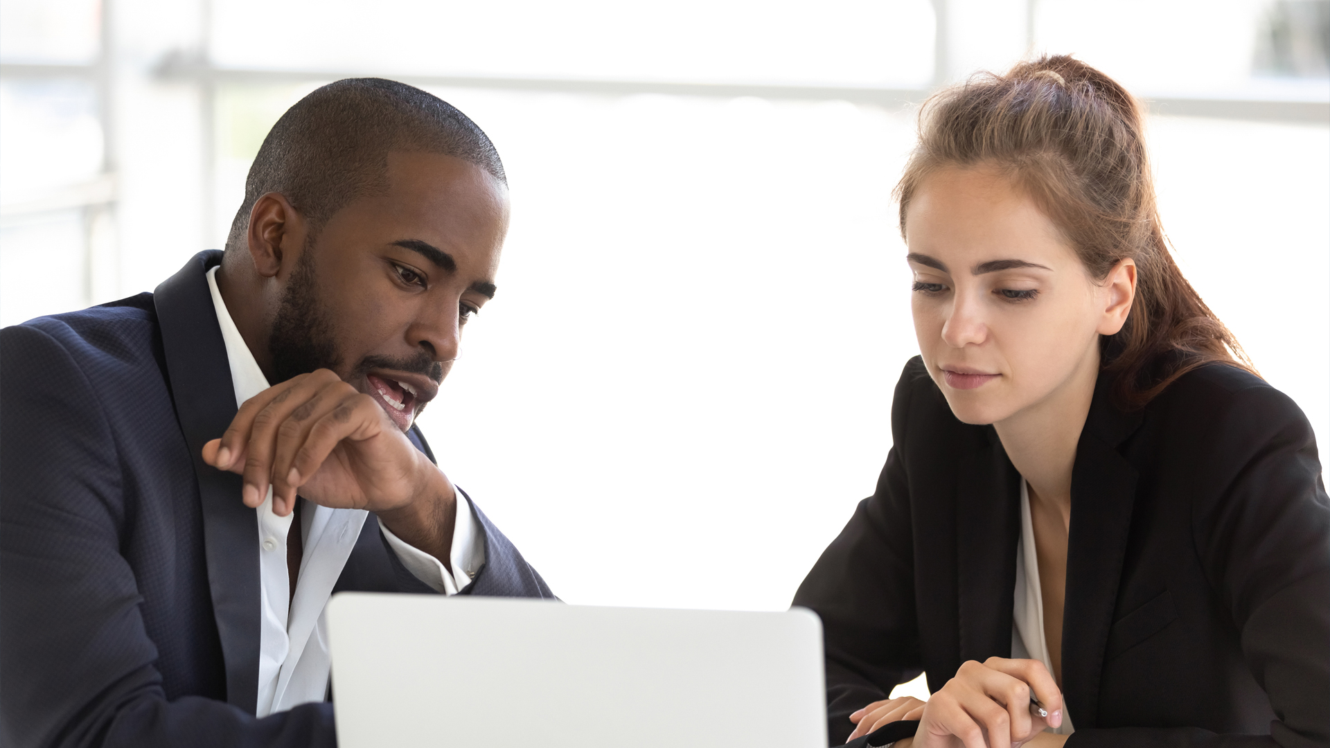 Man showing woman information on laptop.