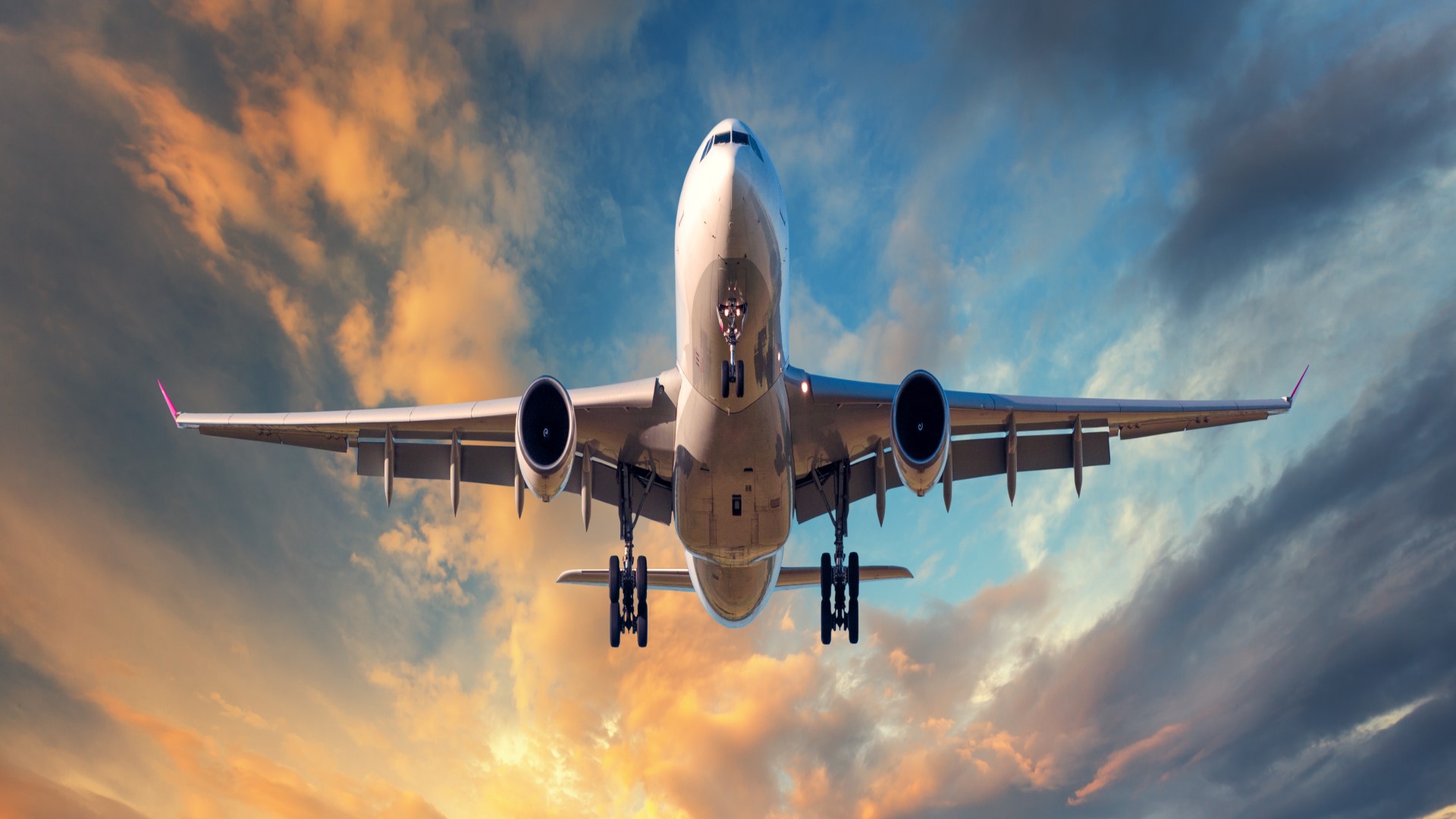 Plane flying through sky at sunset