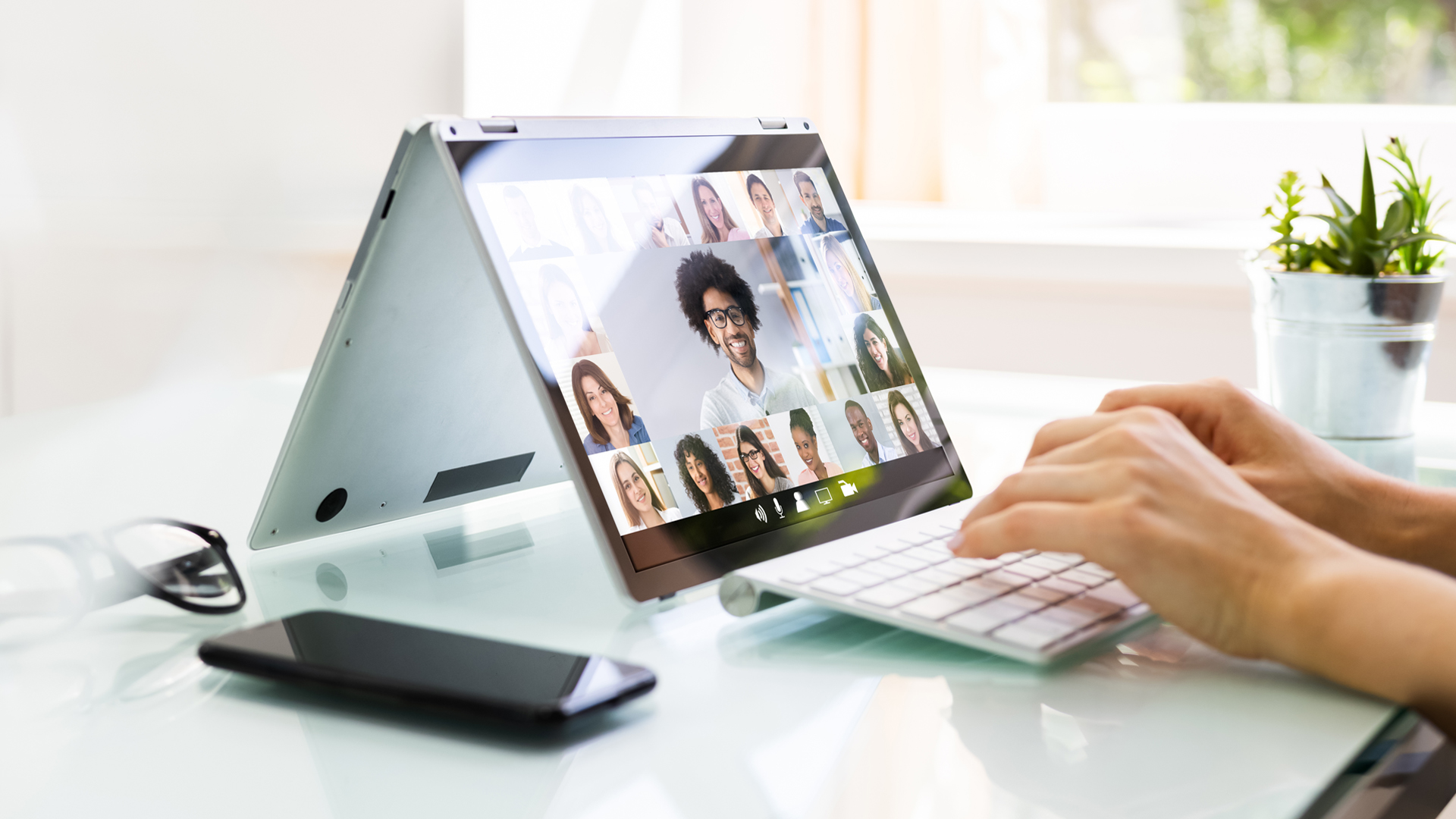 Online Video Conference Interview Call with hand of a woman typing on a computer keyboard connected to an laptop computer