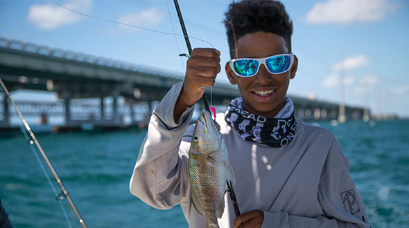 child showing fish and fishing pole