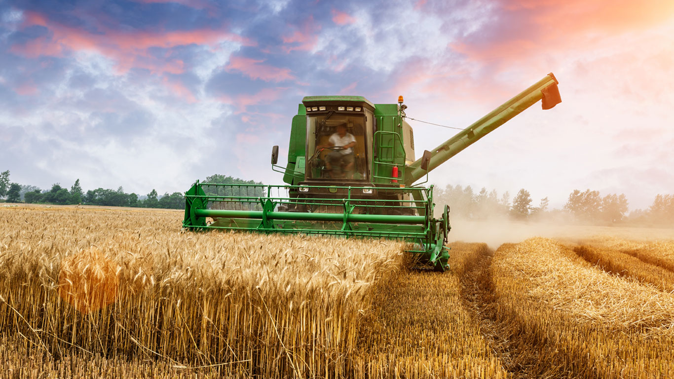 Image of combine and farm with sky with blue and pink clouds