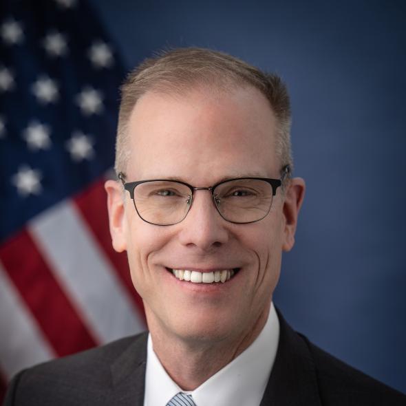 Headshot of Scott Shaw, with U.S. flag in background.