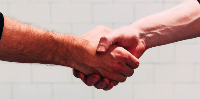 Two hands grasped together in front of a white background