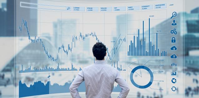 Man standing in front of a wall of various data charts