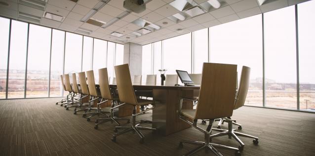 Office conference room with table surrounded by chairs and large windows giving natural light