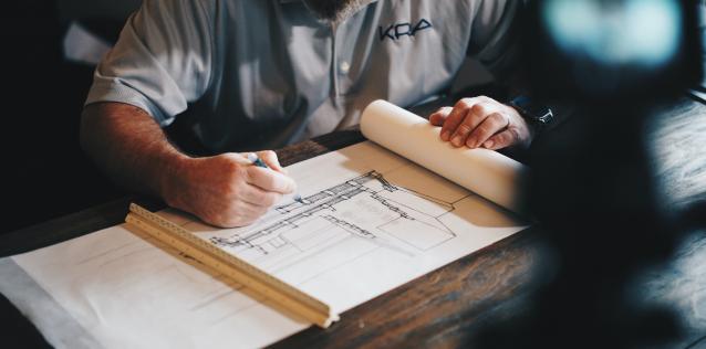 Hands of man sketching architectural blueprints