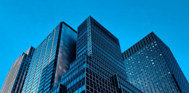 Top of cluster of office buildings with blue sky in background