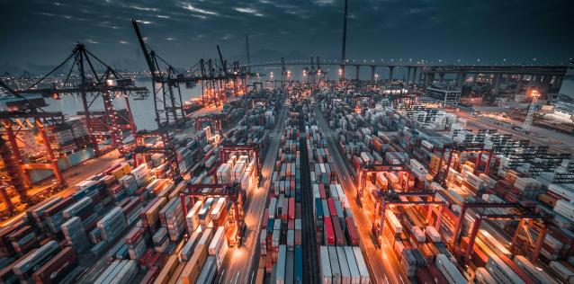 Large port with many stacks of cargo freight containers and cranes