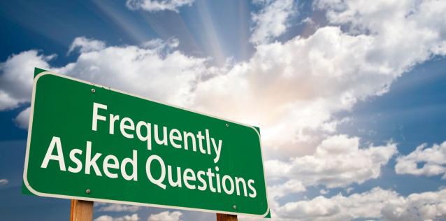 A highway sign that says Frequently Asked Questions with a blue sky with clouds in the background.